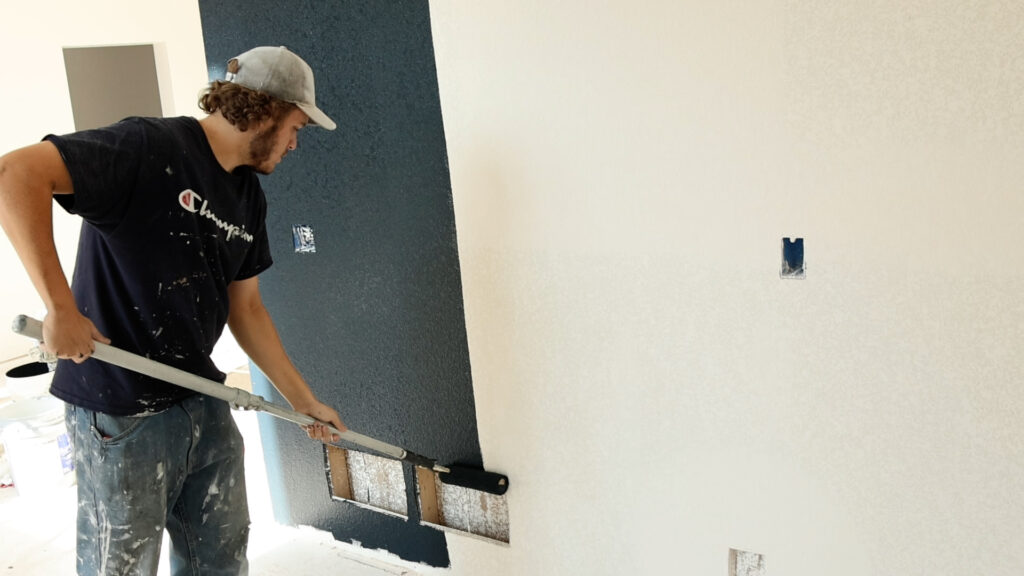 Painter painting home hall with Black Paint with roller brush.