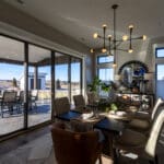 Dining room with Agreeable Gray walls and wide white trim framing sliding doors to a covered patio in a new Spearfish, SD home.
