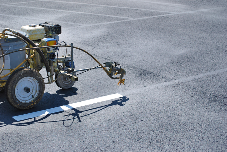 Black Mountain Painting Employee uses parking lot striping equipment to pain pavement in parking lot in Spearfish, SD.