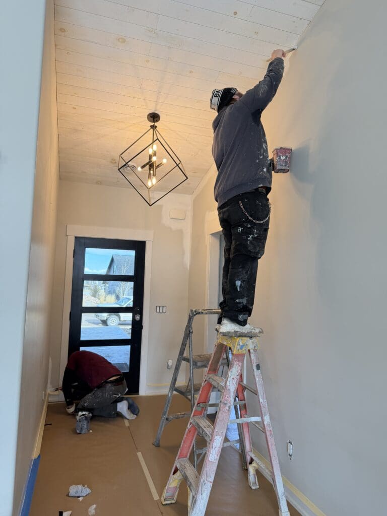 Professional interior painters applying paint to walls and trim during a custom home interior painting project in the Black Hills, South Dakota.