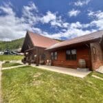 Freshly stained log commercial building near Deadwood SD with rich wood finish completed by Black Mountain Painting.