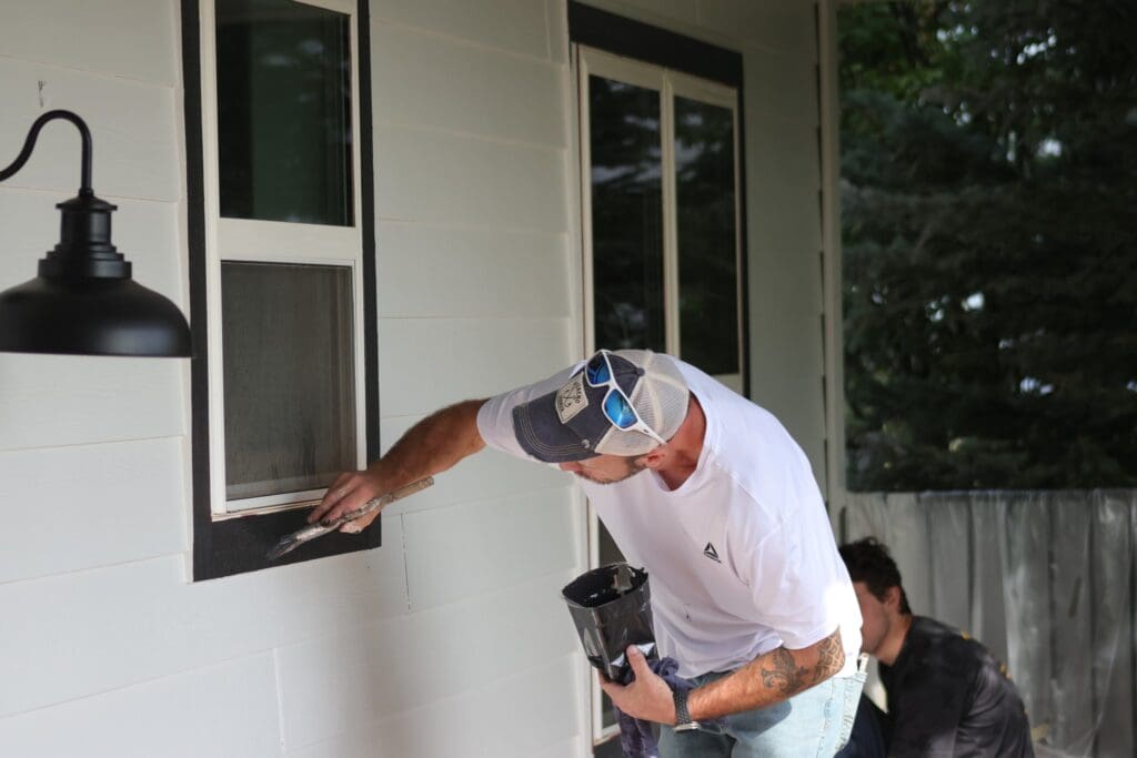 Professional painter from Black Mountain Painting carefully painting window trim during an exterior home project in Spearfish, SD.
