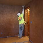 Black Mountain Painting crew member applying a rich brown faux-finish wall treatment near a wood door frame during an interior residential painting project in Deadwood, SD.