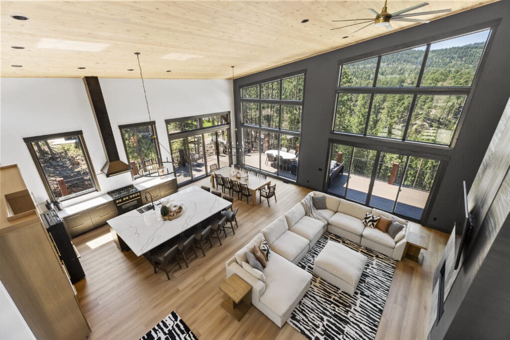 Open great room and kitchen with white walls, a charcoal window wall, and a wood plank ceiling in a Powder House Pass home near Lead, SD.