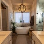Primary bathroom with gray walls, a white three-panel door, and white window trim around a freestanding tub in a new Spearfish, SD home.